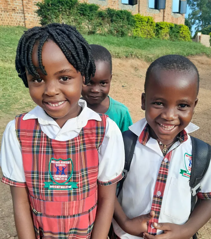 Twee lachende kinderen in schooluniform van de Bulamu Nursery School